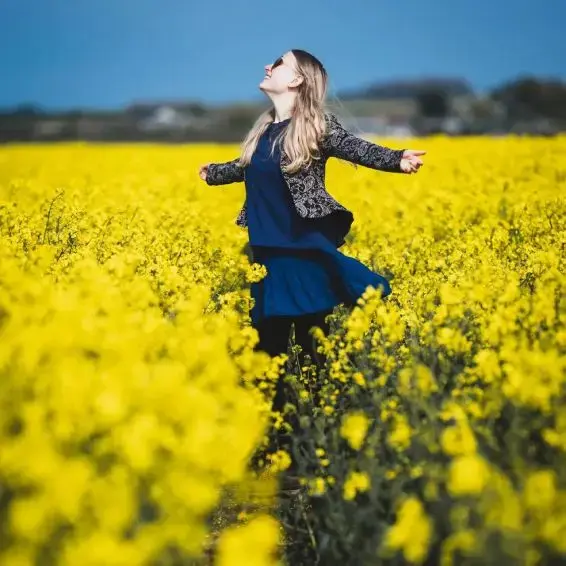 Caroline dancing joyfully in a field of yellow flowers